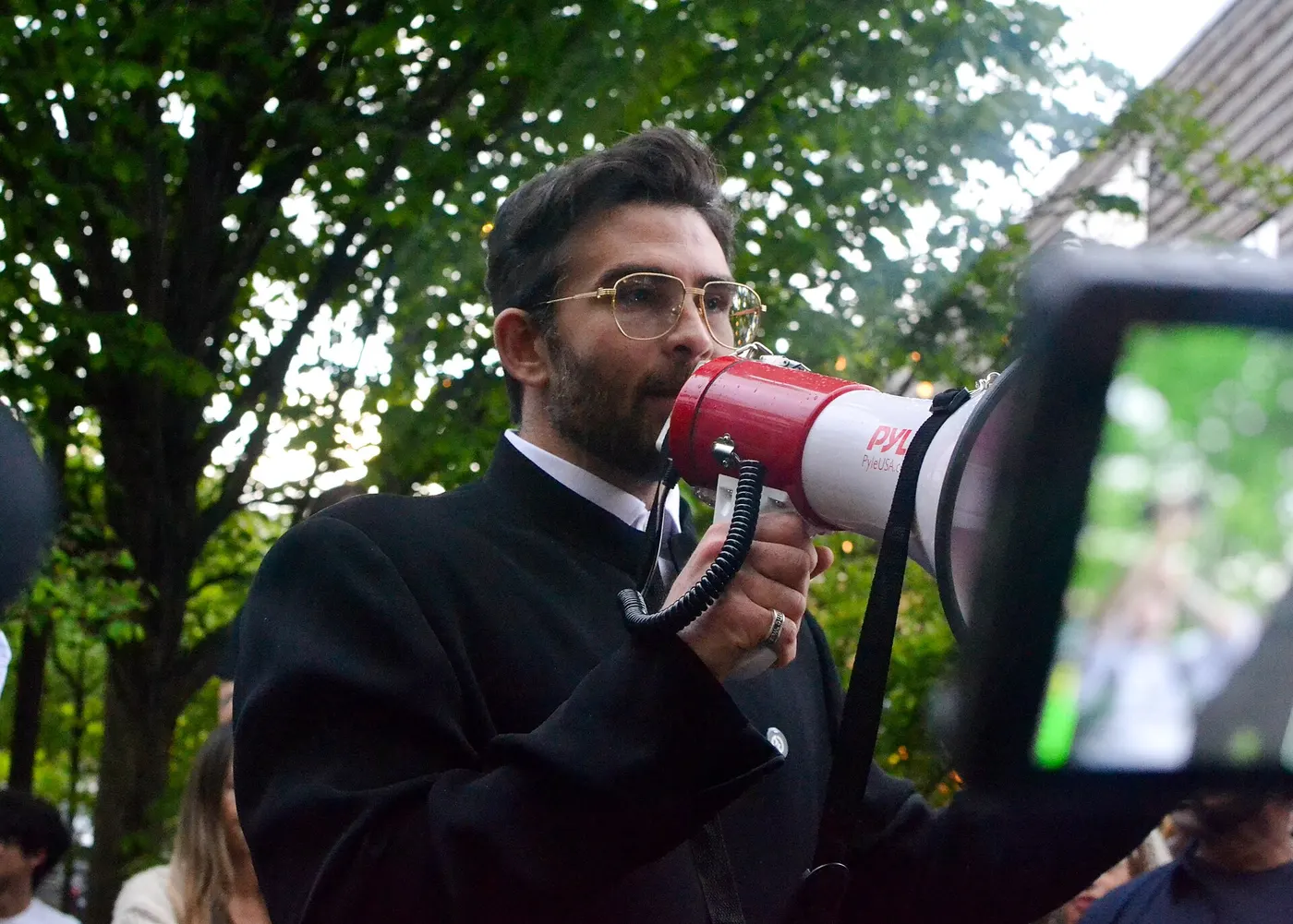 Hasan Piker speaking into a microphone at a rally for Chris Rabb in Philadelphia